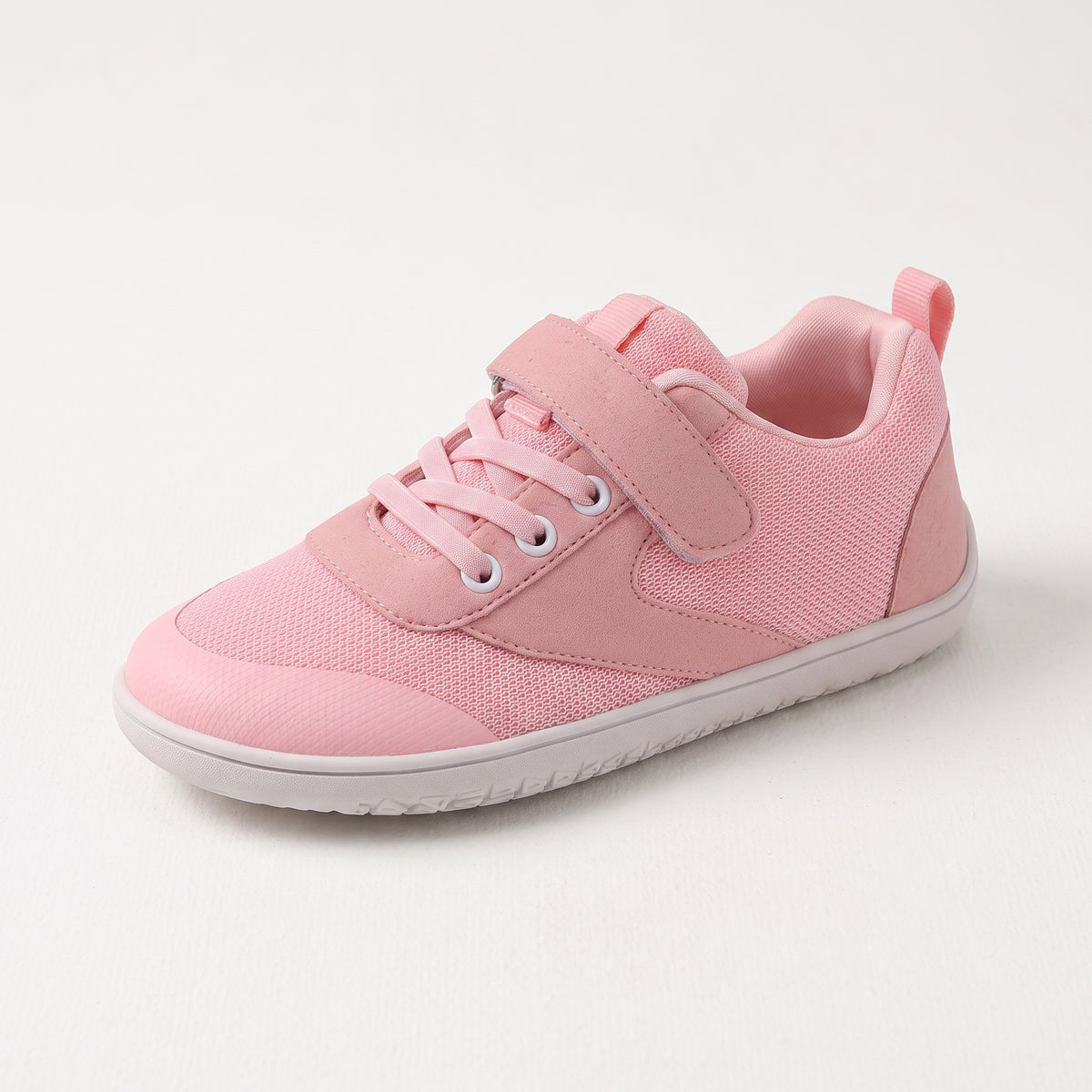 A pink children's barefoot shoe with  matching pink laces, and a white outsole, shown on a light grey background.